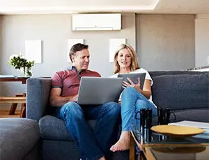 York County PA family relaxing on sofa with Mitsubishi ductless mini-split providing quiet comfort